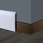 Witte plint in hoek, donkere houten vloer.