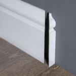 Witte sierplint tegen donkergrijze muur.