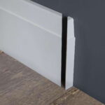 Witte plint tegen muur op houten vloer