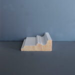 Profiel van houten plint tegen blauwe achtergrond.