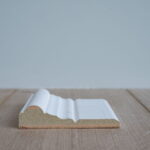 Wit geprofileerd MDF-plint op houten vloer.