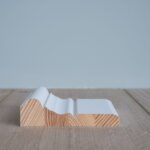 Houten plint met witte afwerking op vloer.