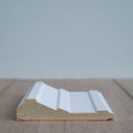 Houten plint op houten vloer voor grijze muur.