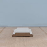 Houten plint op houten vloer tegen blauwe muur.