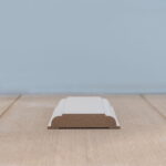 Houten plint met witte afwerking op houten vloer.