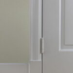 Detail van witte deur met scharnier op houten vloer