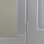 Close-up van een deur en deurkozijn met scharniers.