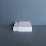 Twee witte houten blokken op grijze ondergrond.