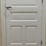 Witte houten deur met paneeldetails en zilveren handvat.