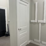 Witte deur in showroom met grijze muur en lijstwerk.