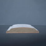 Houten plint met witte afwerking tegen grijze achtergrond.