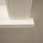 Witte muurhoek met platte details en schaduw.