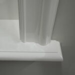 Witte vensterbank met verfspatten op grijze muur.