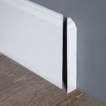 Witte plint op grijze muur en houten vloer.