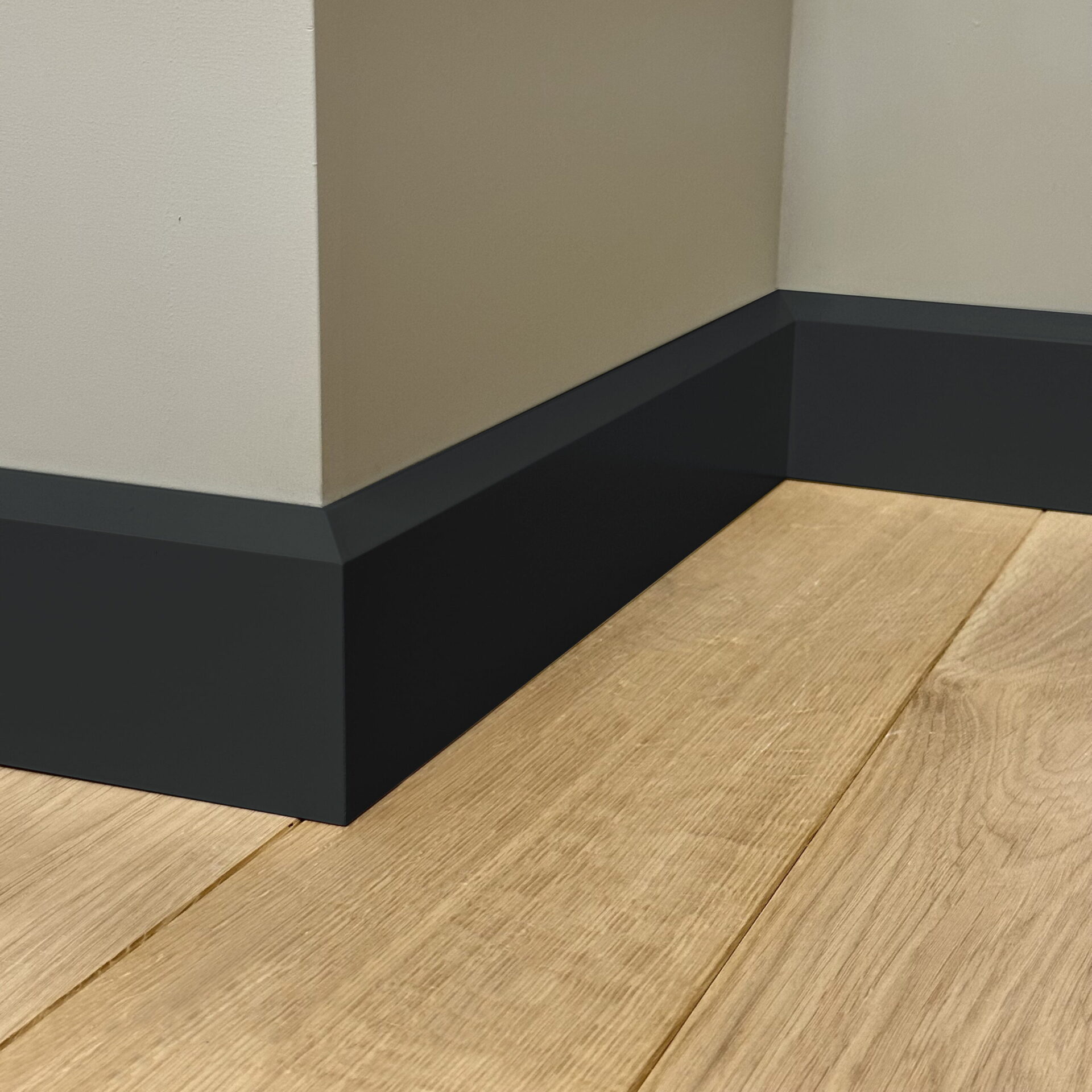 Zwarte plint boven houten vloer.