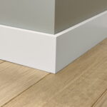 Witte plint op houten vloer naast muur