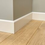 Hoek met houten vloer en witte plint.