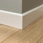 Hoek met witte plint en houten vloer