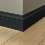 Hoek van een muur met plint en houten vloer.