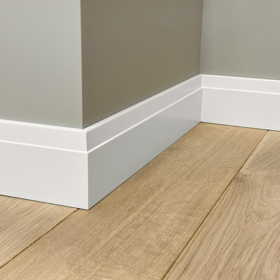 Witte plint met houten vloer en grijze muur