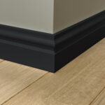 Houten vloer met zwarte plint in hoek.