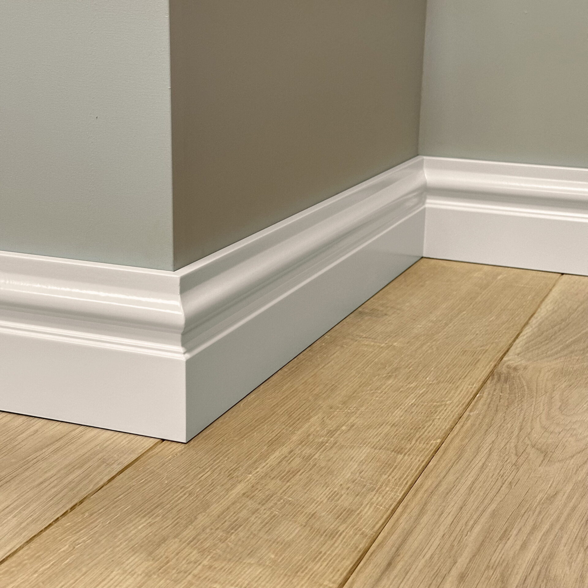 Witte plint tegen grijze muur op houten vloer