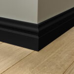Zwarte plint langs houten vloer bij muurhoek