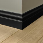 Zwarte plint op houten vloer in hoek van kamer.
