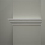 Grijze muur met witte lijst decoratie.