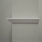 Lege witte wandplank tegen grijze muur.