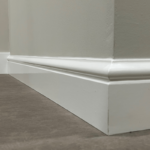 Witte plint tegen grijze muur en vloerhoek