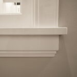 Witte muurplank tegen grijze muur met decoratieve lijst
