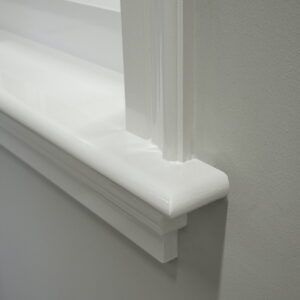 Witte afgewerkte vensterbankhoek met verflaag.