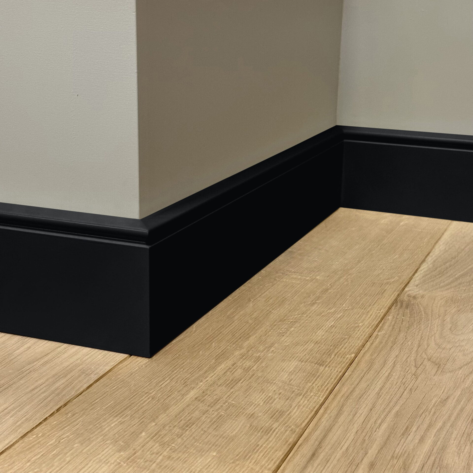 Houten vloer met zwarte plinten in hoek