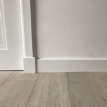 Witte plint tegen een houten vloer en muur