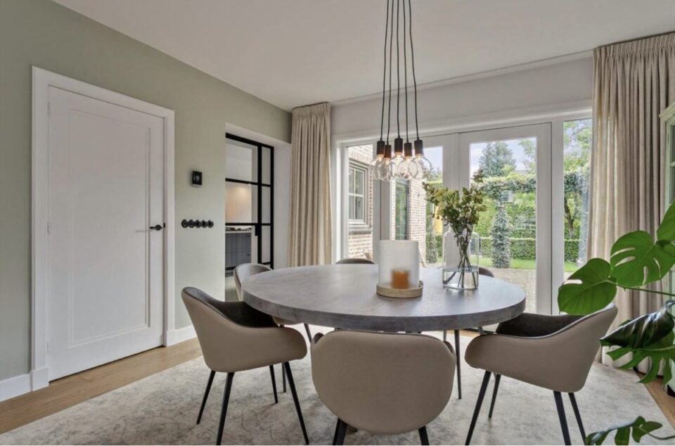 Moderne eetkamer met ronde tafel en groene planten.