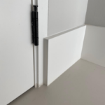 Zwarte scharnier op witte deur en muur