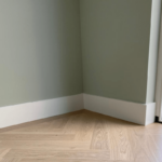 Groene muur met houten vloer en witte plint